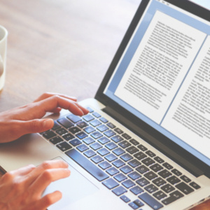 person's hands on laptop with cup of coffee next to laptop